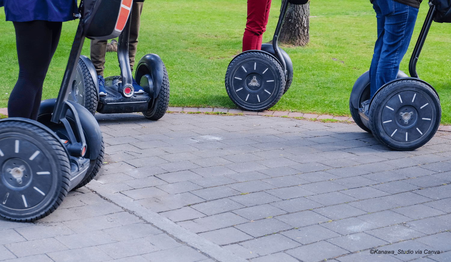 horizontal image of the wheels of four Segways on a pathway