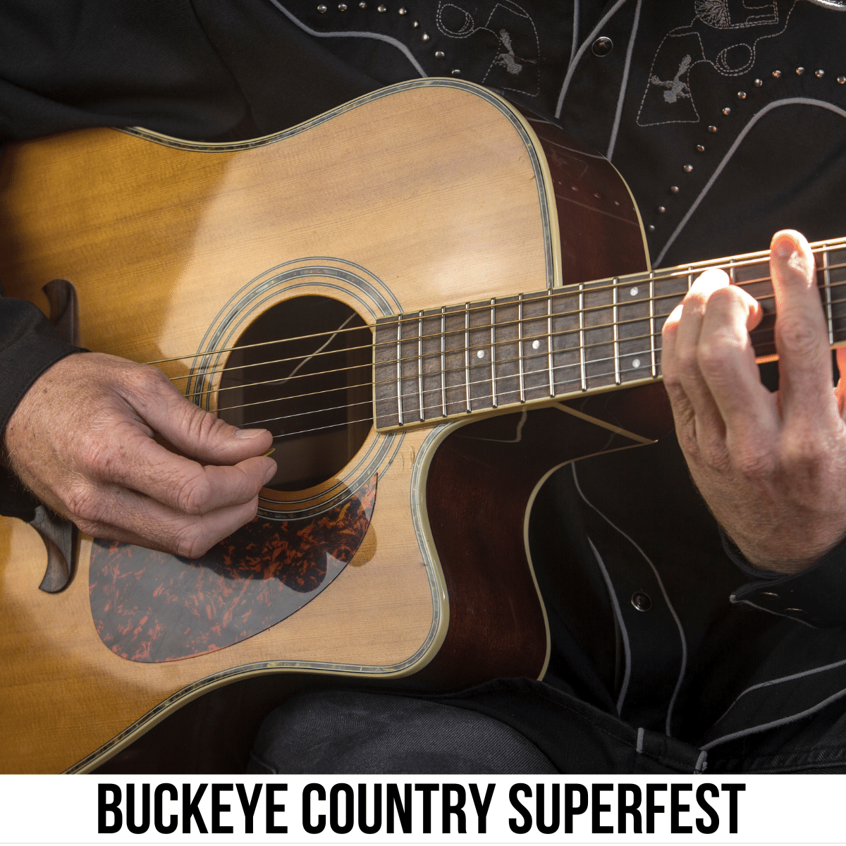 A square image of a photo of someone's hands on an acoustic guitar, playing music. A white strip across the bottom has text Buckeye Country Superfest