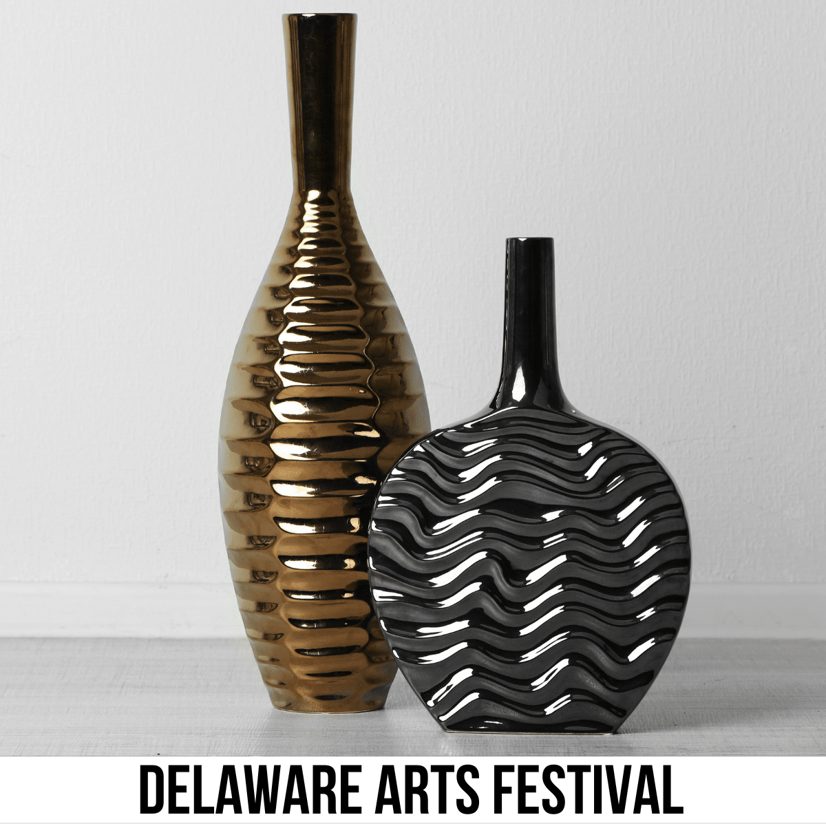 A square image of a photo of two vases, a shorter, rounder vase and a taller, thinner vase, both with a ridge design and a metal-colored finish-one is gray and the other is bronze. A white strip across the bottom has text Delaware Arts Festival