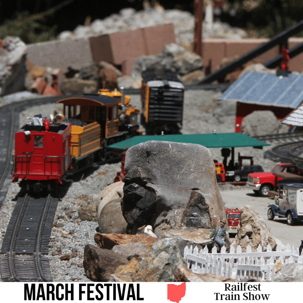 A square image of a photo af a model train display with a train on a track. A white strip across the bottom has text March Festival Railfest Train Show.