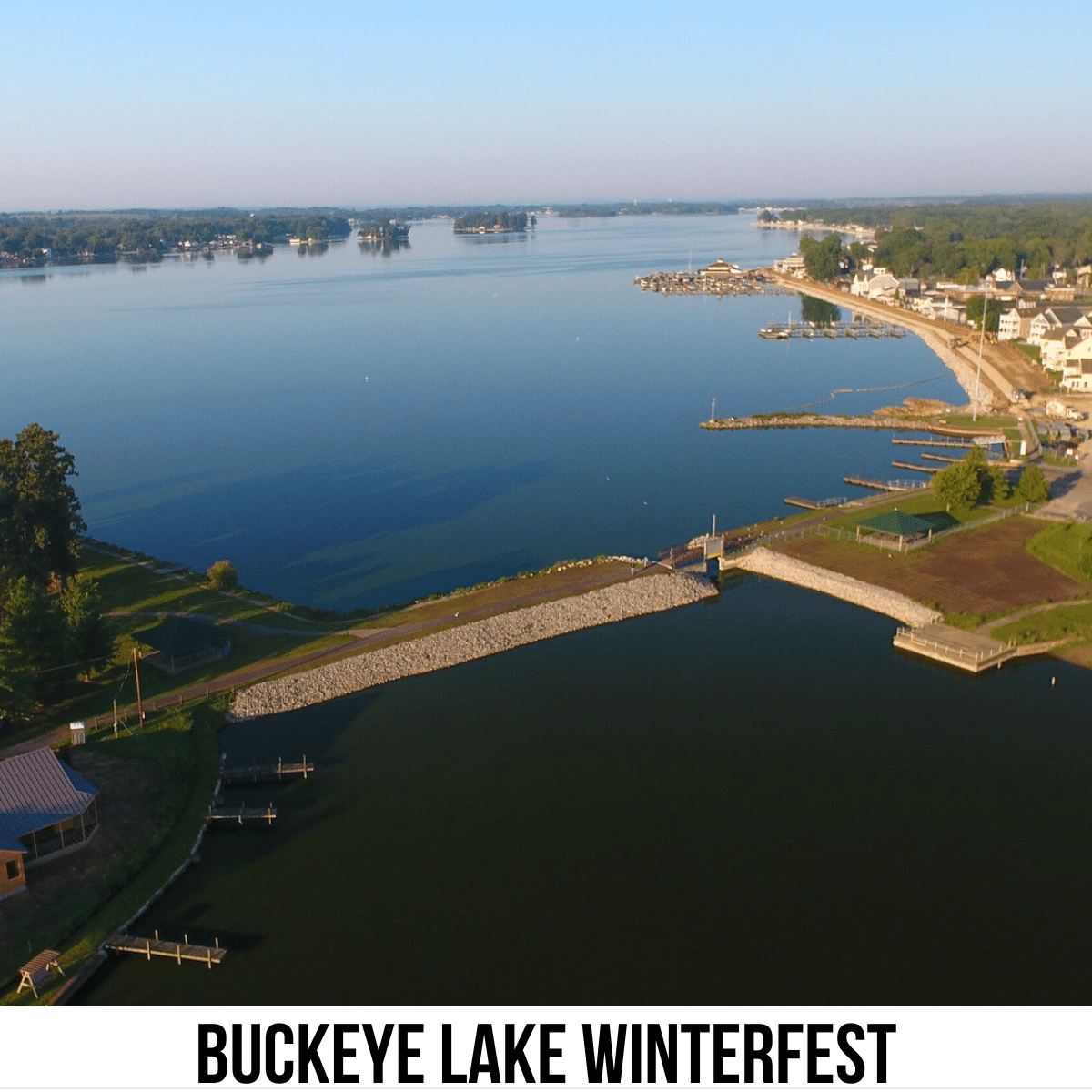 A square image of a photo of a large body of water and 2 areas of land connected by a road and a bridge. A white strip across the bottom has text Buckeye Lake Winterfest.