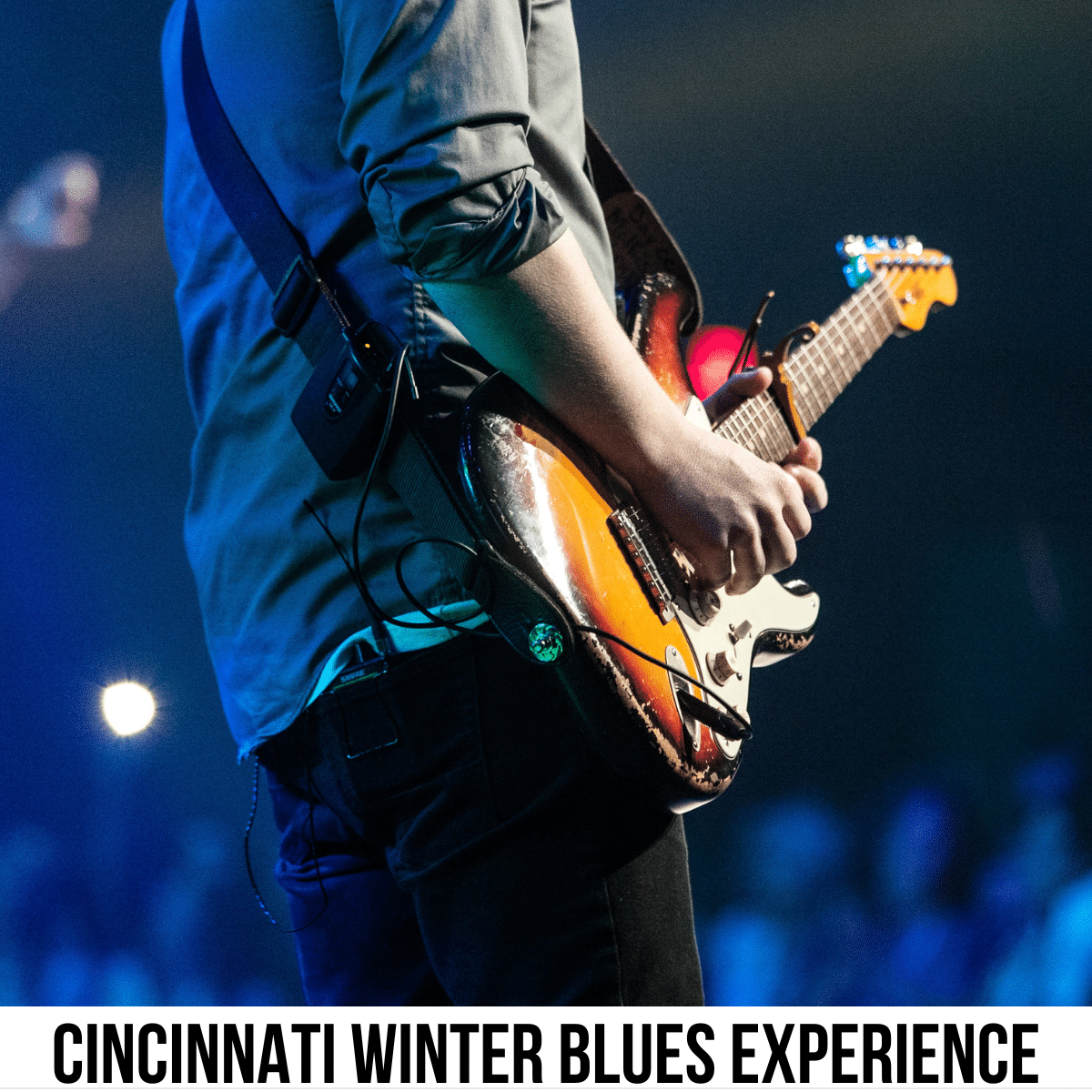 A square image of an up-close photo of a person playing guitar in front of an audience. The photo is taken from the person's side, from below their shoulder to their thigh. A white strip across the bottom has text Cincinnati Winter Blues Experience.