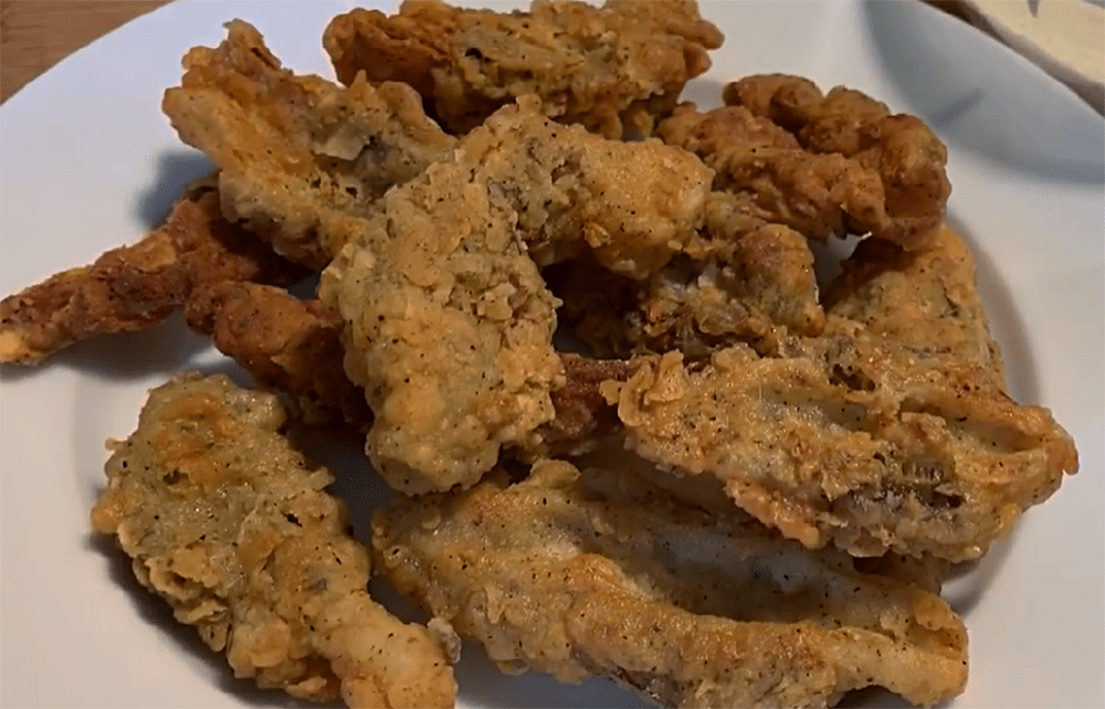 horizontal photo of a plate of breaded and cooked morel mushrooms