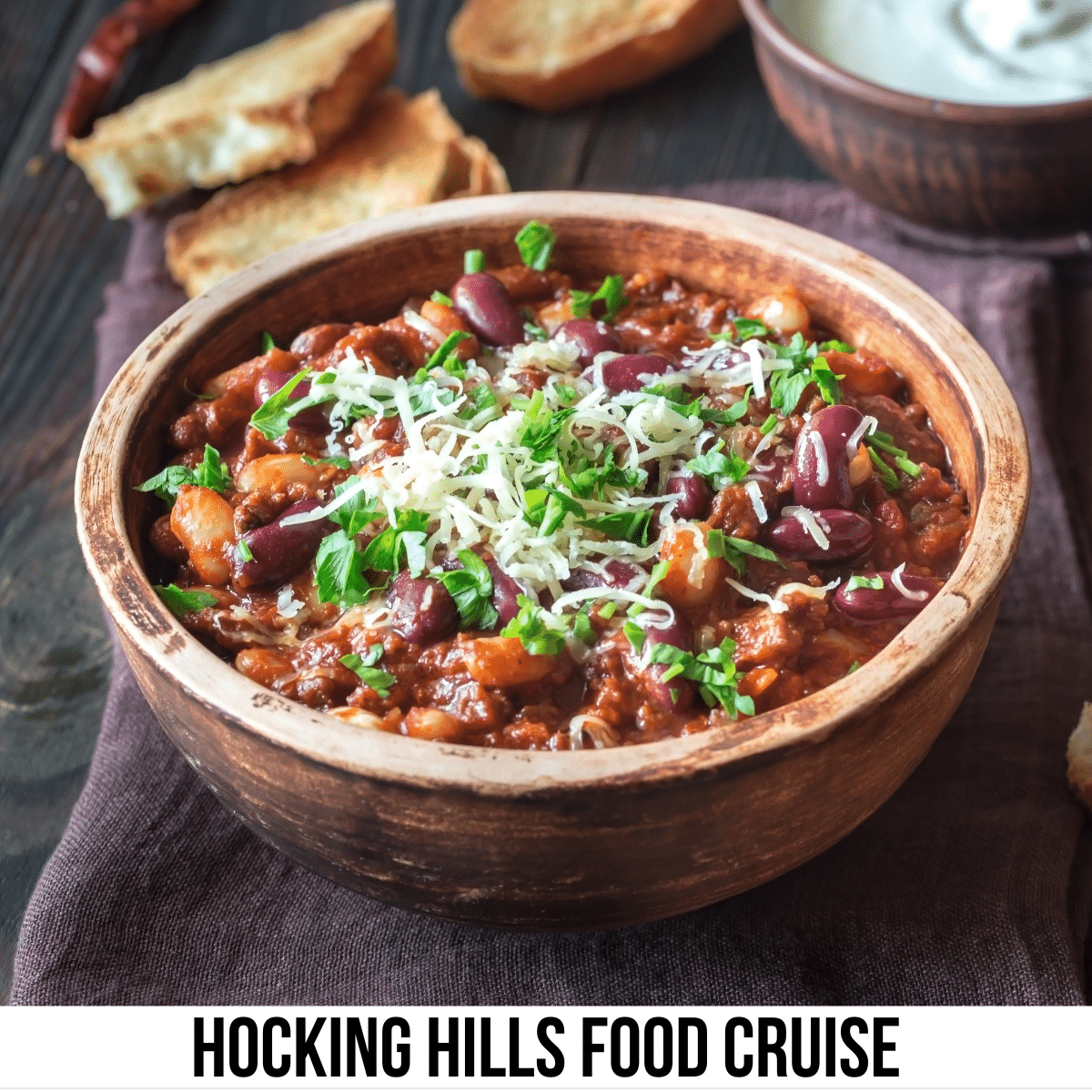 square image with a photo of a bowl of chili on a dark wood surface. A white strip across the bottom has the text Hocking Hills Food Cruise