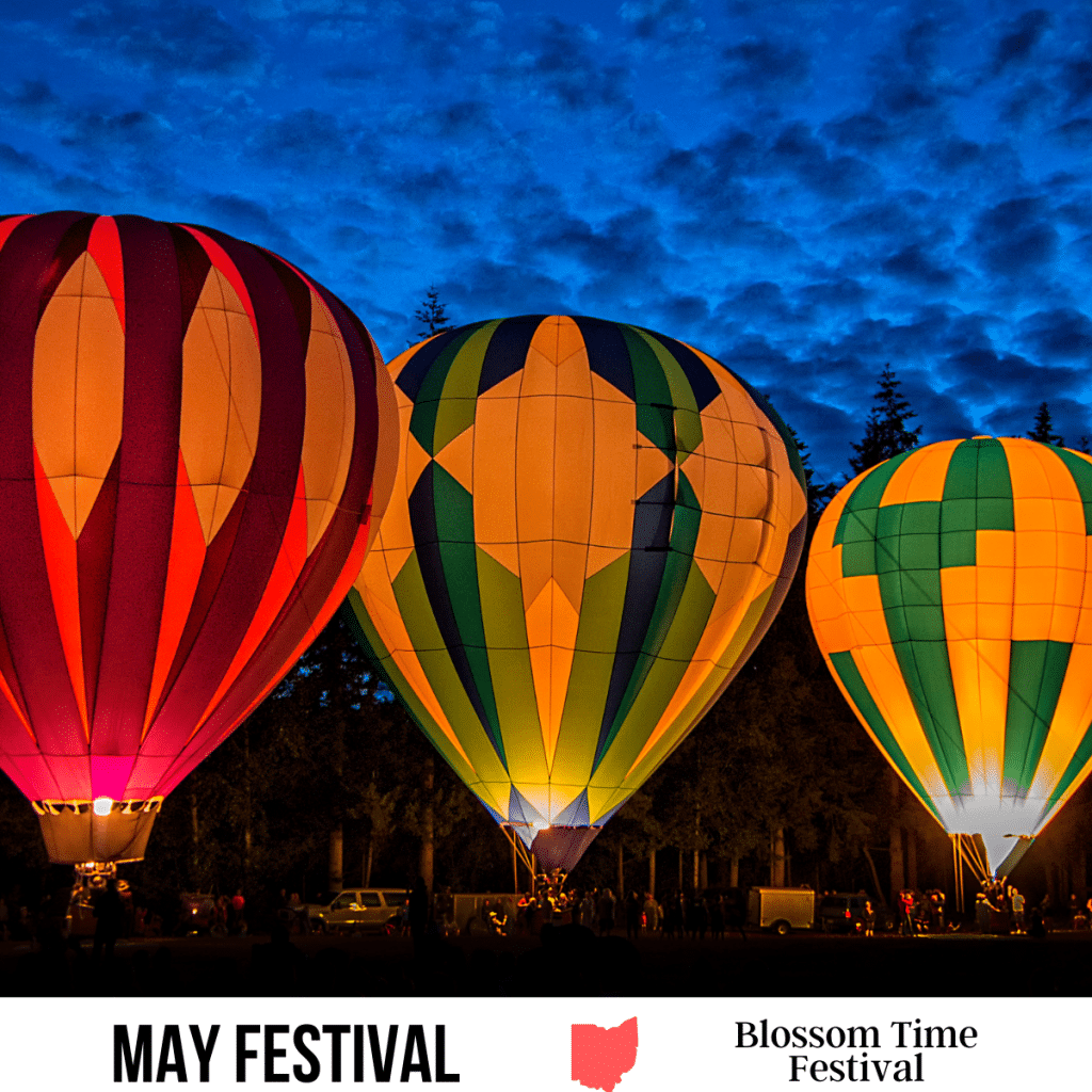 square image with a photo of glowing hot air balloons. A white strip across the bottom has the text May Festival. Blossom Time Festival