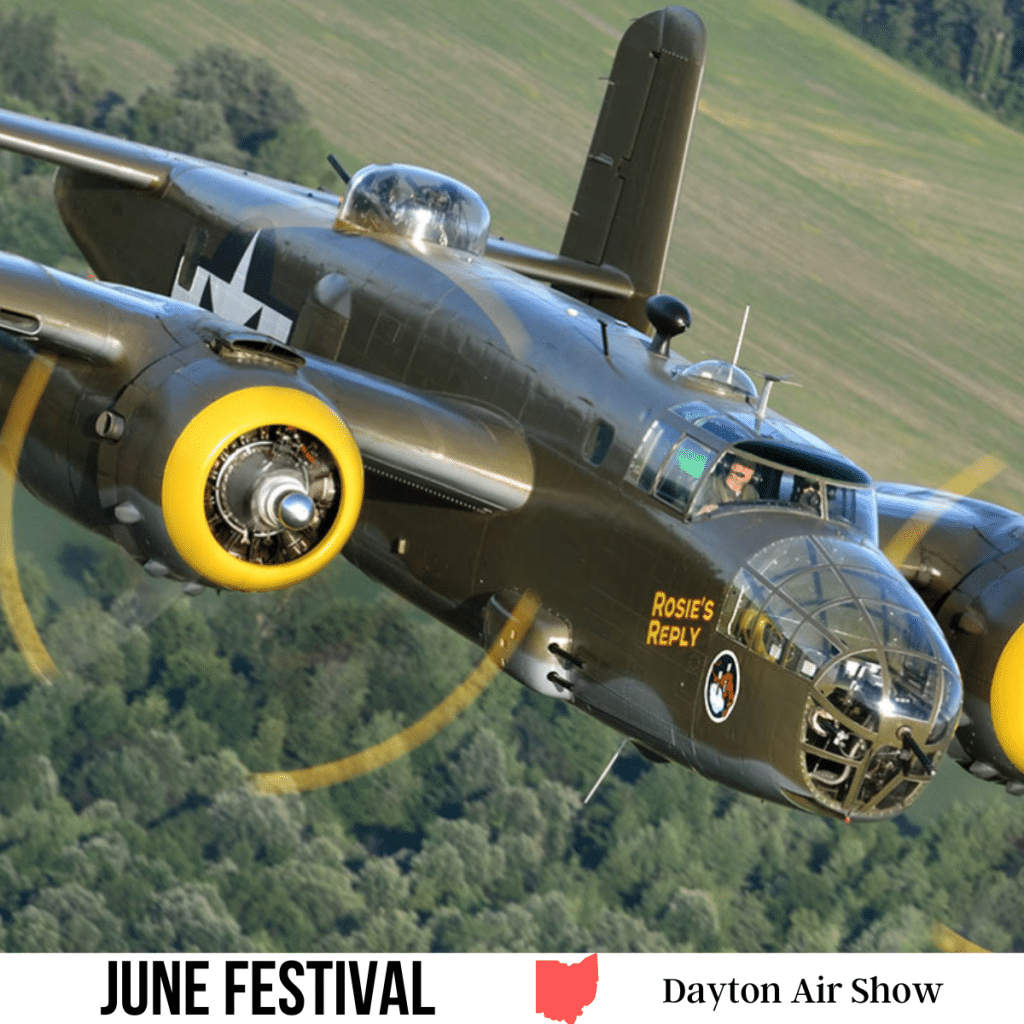 square image with a photo of a war time aircraft flying over woodlands. A white strip across the bottom has the text June Festival. Dayton Air Show
