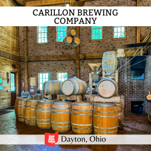 square image with a photo of beer barrels inside the brewery. A white strip across the top has the textt Carillon Brewing Company, and a white strip across the bottom has the text Dayton, Ohio