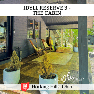 square image with a photo of the outside deck area at The Cabin. A white strip across the top contains the text Idyll Reserve 3 - The Cabin, and a white strip across the bottom has the text Hocking Hills, Ohio