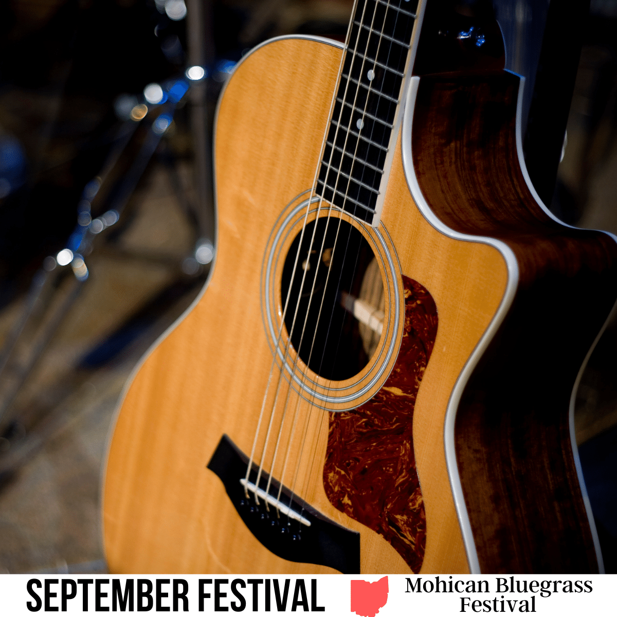 square image with a close up photo of an acoustic guitar on a stand. A white strip across the bottom has the text September Festival. Mohican Bluegrass Festival
