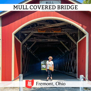 square image with a photo of the front of the bridge with Cindy Gordon standing at the entrance. A white strip across the top has the text Mull Covered Bridge, and a white strip across the bottom has the text Fremont, Ohio