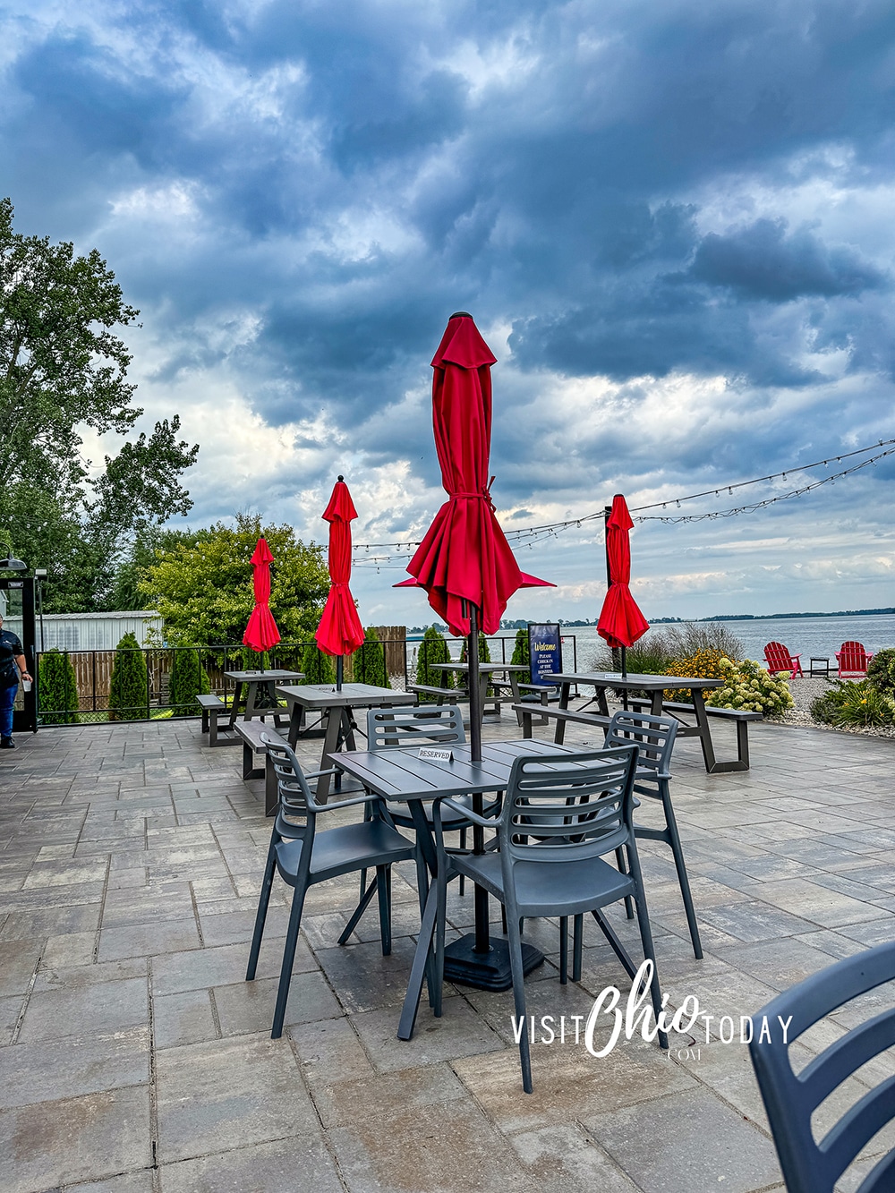 vertical photo of the patio seating area at Pipe Creek Wharf with Sandusky Bay in the background. Photo credit: Cindy Gordon of VisitOhioToday.com