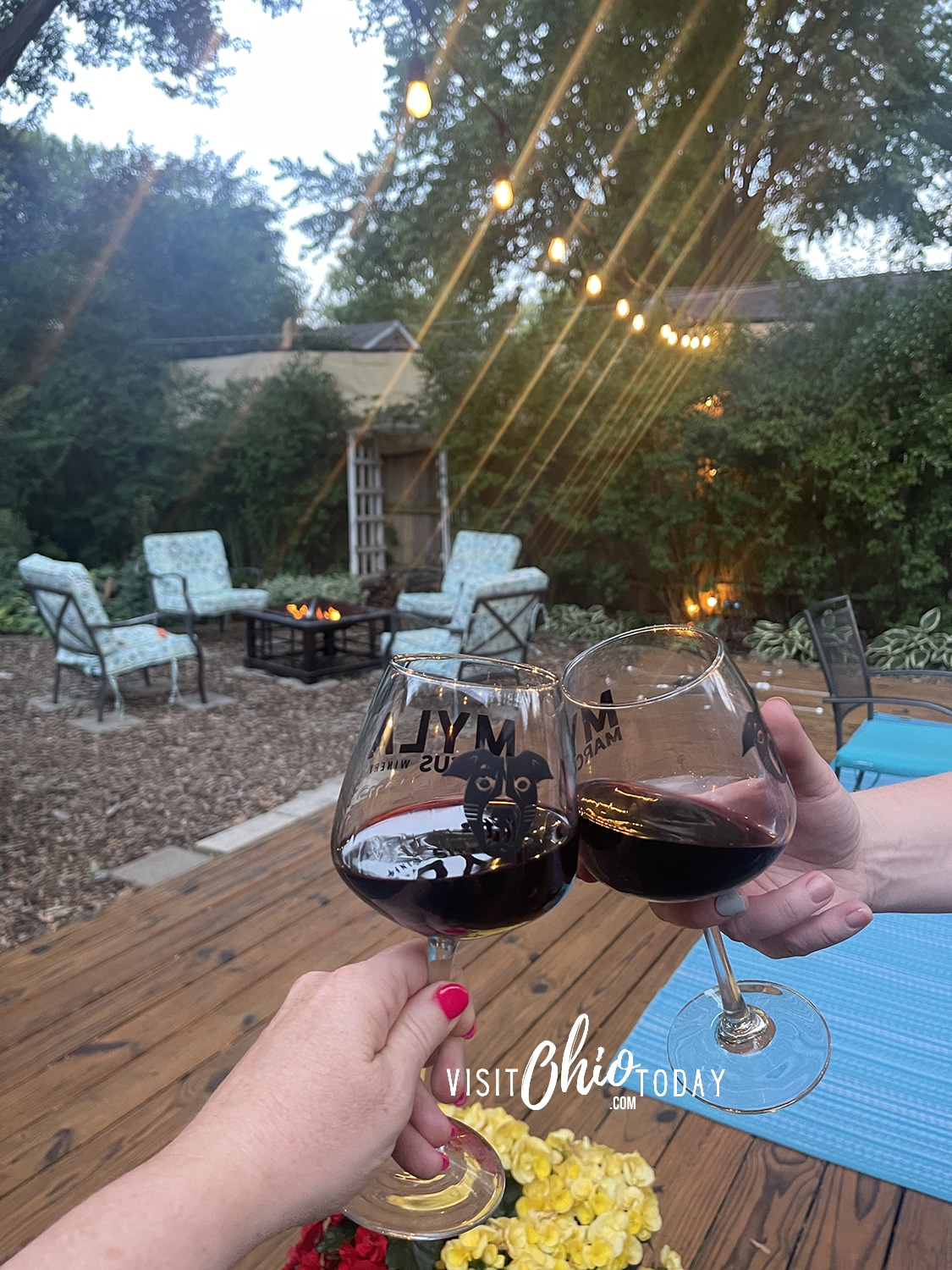 vertical photo of two people clinking glasses of wine outside Myla Marcus Winery. Photo credit: Cindy Gordon of VisitOhioToday.com